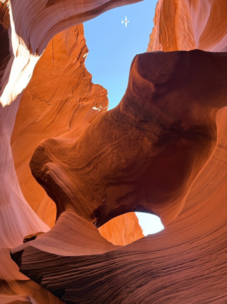 Lower Antelope Canyon with a small plane flying overhead.